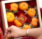 Chinese New Year box with oranges, red roses, and a "Fu" decoration.