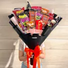Halloween snack bouquet with assorted candies and treats, wrapped in black paper with an orange ribbon.