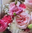 A bouquet of pink roses and carnations with tiny white baby's breath flowers.