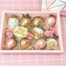 A pink gift box filled with 10 chocolate-dipped strawberries, decorated with gold glitter, pearls, and roses.