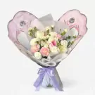 Bouquet of white and pink carnations, white roses, and eucalyptus in pastel butterfly-themed wrapping, tied with a purple ribbon.