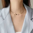 Gold necklace with five mixed-color heart charms on a woman's neck.