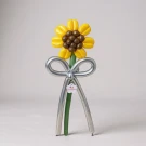 A balloon sunflower with yellow petals and a brown center, a silver bow and stem, on a light background.