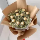 Ferrero Rocher chocolates in a bouquet of yellow dried limonium flowers, wrapped in brown paper.