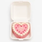 Heart-shaped pink Valentine's cake with white frosting border and "Happy Valentine's Day" text.