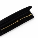 Gold-tone infinity knot bracelet in a black velvet jewelry box.