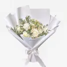 White roses and daisies arranged in a white bouquet with a satin ribbon.