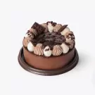 Decadent chocolate cake with chocolate ganache frosting, piped whipped cream, chocolate chunks, and chocolate bar pieces.