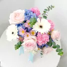 A pastel flower arrangement with pink roses, blue hydrangeas, white gerbera daisies, and carnations.