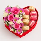 Heart-shaped box with pink macarons and pink and white flowers.