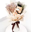 Graduation teddy bear in a bouquet with Thai baht banknotes and a dark brown ribbon.