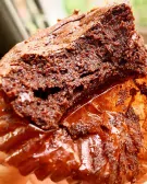 Close-up of a rich, dark chocolate brownie with a fudgy texture, sitting in a wrapper.