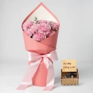 Pink carnation bouquet with pink ribbon and a wooden music box engraved with "Can't Help Falling in Love".