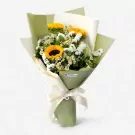 Bouquet of sunflowers and white statice in light green and cream paper wrap, tied with a cream ribbon.