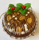 Chocolate brownie with white and dark chocolate chips, topped with holly and berries, tied with twine.