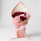 Bouquet of red roses and pink carnations in pink paper with a pink ribbon.