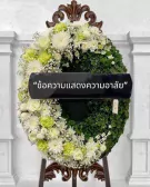 Funeral wreath with white and green flowers and a black ribbon with Thai text.
