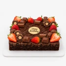 Chocolate brownie cake topped with strawberries, chocolate pieces, and a "Happy Birthday" topper.