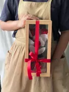 Wooden box with three preserved red and white roses, tied with a red ribbon.