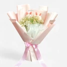 A bouquet with two fluffy white rabbit-shaped decorations nestled amongst white daisies and gypsophila, wrapped in pink and white paper with a pink ribbon.