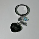 Silver heart-shaped keychain with engraved text and holographic initial charm.