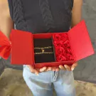 A red gift box holds two magnetic half-heart bracelets and red roses.