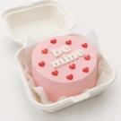 Pink frosted cake with "be mine" in white letters and red heart sprinkles.