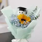 Graduation bouquet with a stuffed toy wearing a cap, sunflower, baby's breath, and eucalyptus.