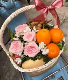 Fruit basket with oranges, mango, dragon fruit, longan, and pink roses, tied with a pink bow.