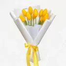A bouquet of yellow tulips wrapped in white paper and tied with a yellow ribbon.