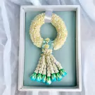 A circular white jasmine garland with light blue accents in a white gift box.