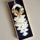 An artificial white and gold floral garland in an acrylic box, with white flowers cascading down.