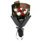 Bouquet of red and white roses wrapped in dark paper with a grey ribbon.