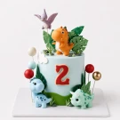 Light blue dinosaur cake with fondant dinosaurs, leaves, and a "2" topper.
