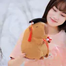 Brown capybara plush doll wearing a graduation cap and holding a diploma.