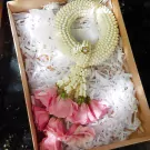 A white jasmine garland with pink roses in a gift box.