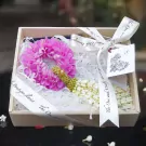 Gift box with pink mum lei, jasmine lei, and decorative ribbon.
