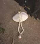 Oceanwave Necklace with freshwater pearls on a seashell, on sand.