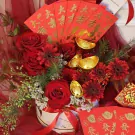 Red roses and gerberas in a box with red envelopes and gold ingots.