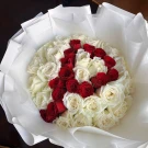 A bouquet of red and white roses wrapped in white paper.