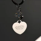 Heart-shaped keychain with engraved message and charm.