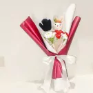 Crocheted bunny and flowers in a red and white bouquet, tied with a white ribbon.