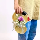 Graduation gift of a single purple rose and baby's breath with a graduation cap decoration.