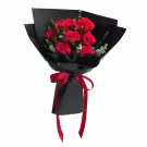 Red carnations with eucalyptus leaves, wrapped in black paper and tied with a red ribbon.