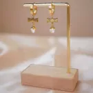 Gold cross earrings with crystal heart drops on a gold stand.