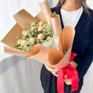 Ferrero Rocher chocolates and yellow limonium flowers in a brown paper bouquet with a red ribbon.