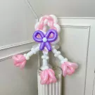 Balloon sculpture of a character with pink, white, and purple balloons, adorned with a purple bow.