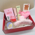Valentine's gift set with pink perfume, makeup, fuzzy claw clip, and heart decor.