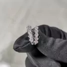 Diamond-encrusted hoop earrings held by a black gloved hand.