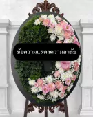 Funeral wreath shaped like a crescent moon, adorned with pink and white flowers, with a black sign in the center.
